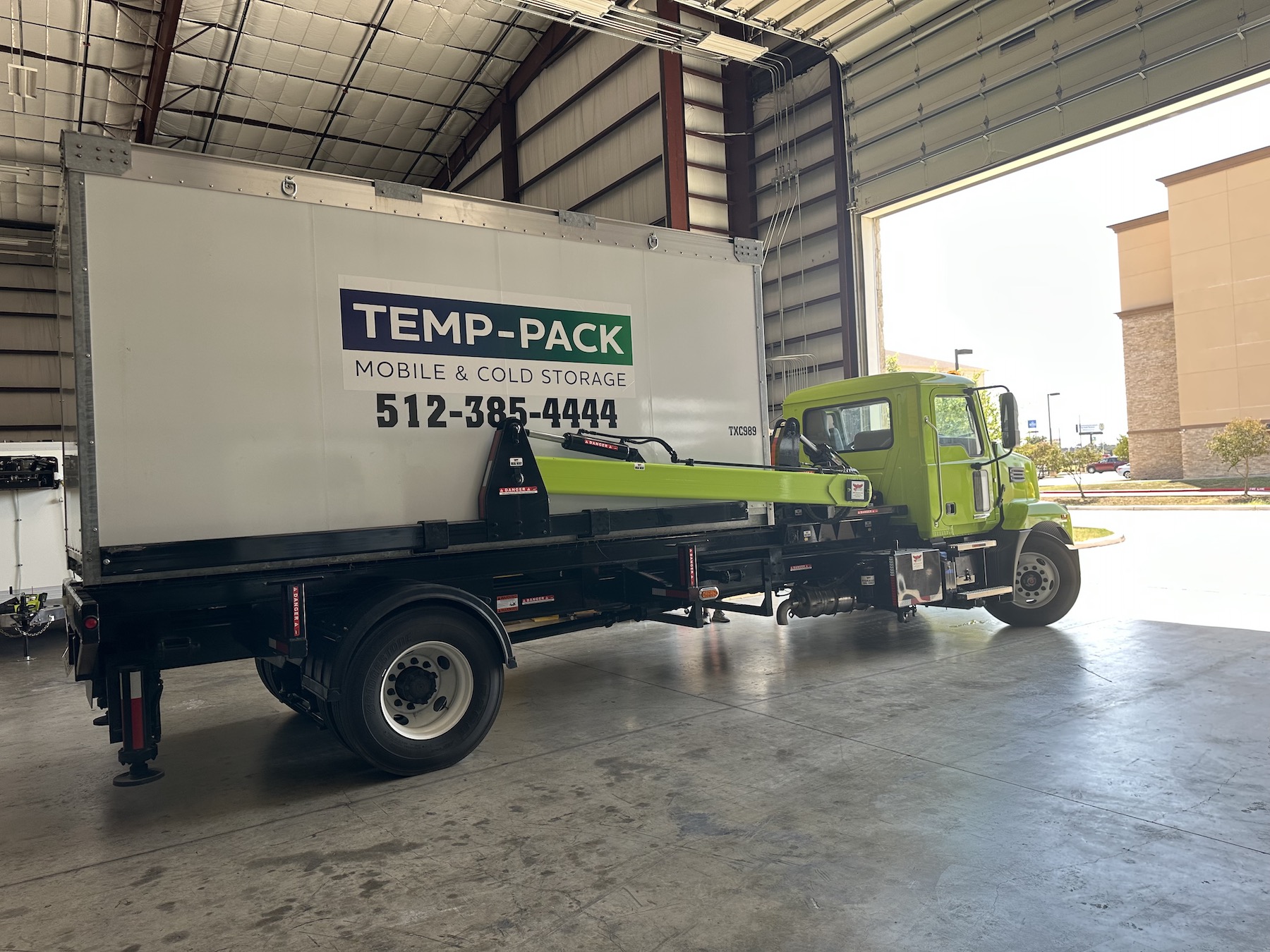 TEMP-PACK green delivery truck and storage container beside the warehouse